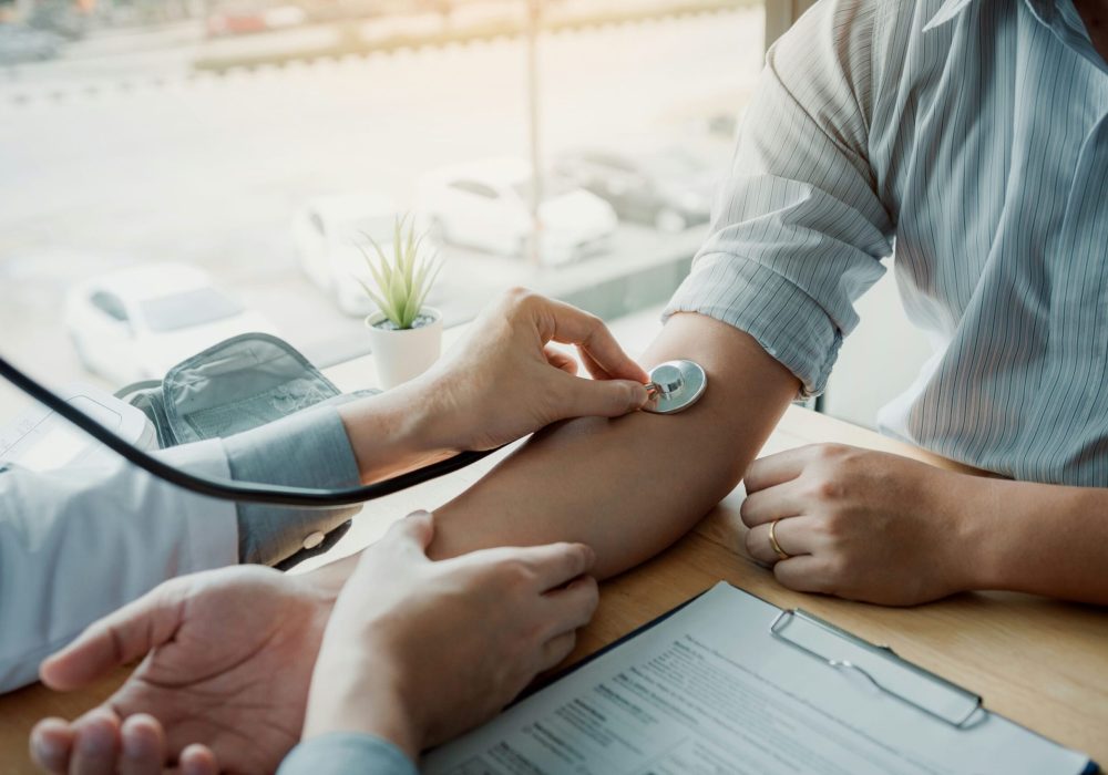 Doctor using stethoscope take a tap on the patient's arm and pressing pressure gauge button.